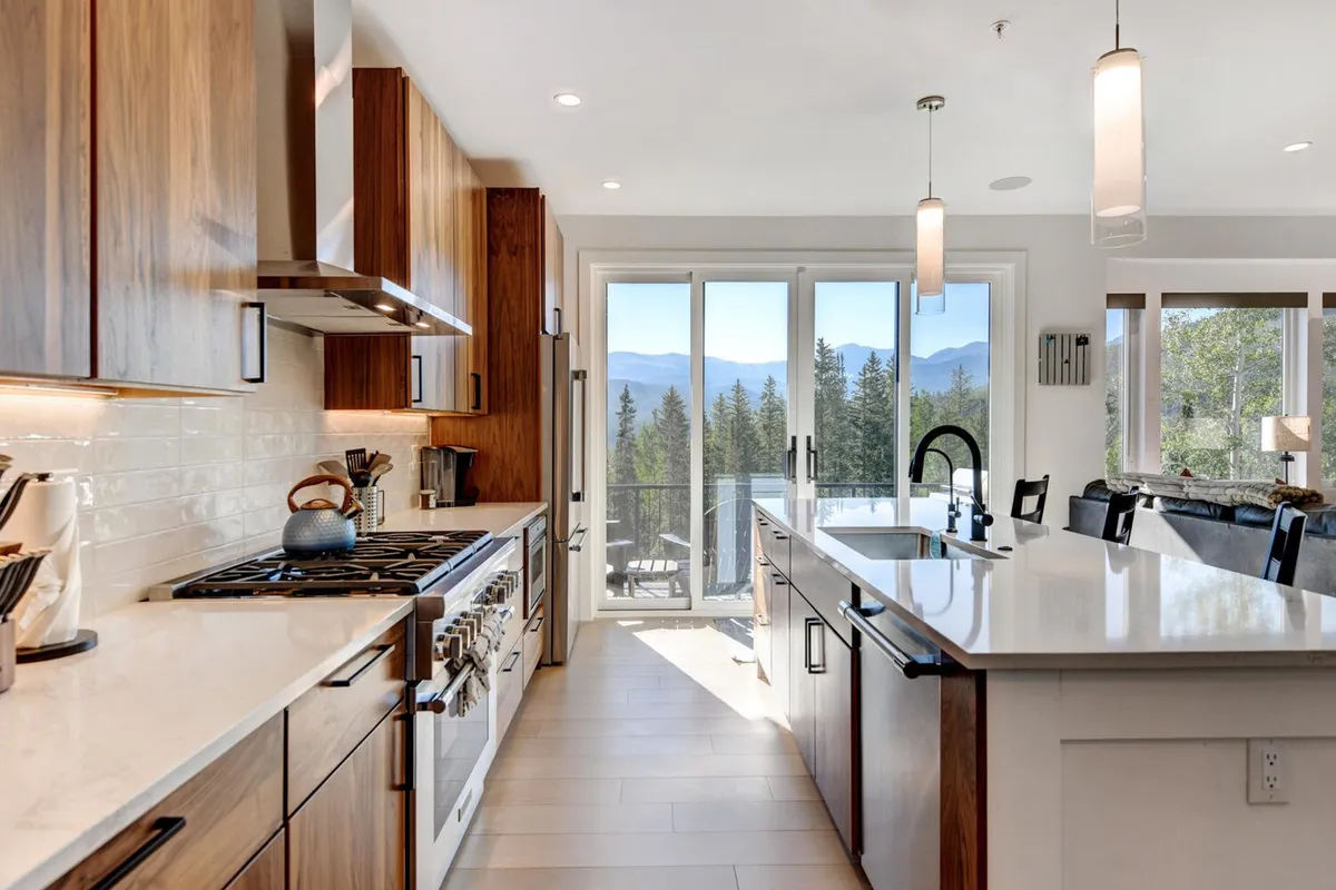 A contemporary kitchen featuring modern appliances, a sleek kitchen island, and large windows offering stunning mountain vistas. The open design encourages both cooking and socializing, while the inviting atmosphere hints at family gatherings and shared meals.