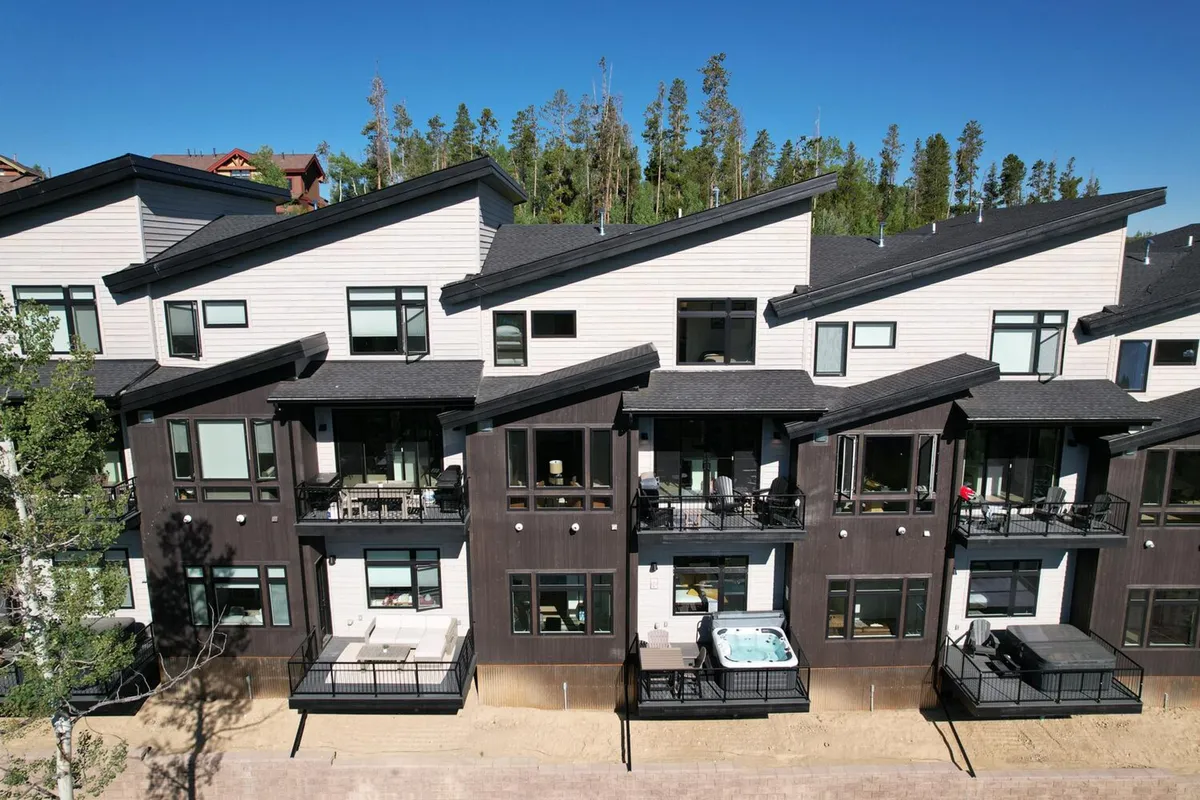 A contemporary exterior shot showing the home's hot tub, modern balconies, and surrounding nature. The image blends the home’s stylish architecture with its connection to the outdoors, highlighting both relaxation and adventure launchpad qualities.