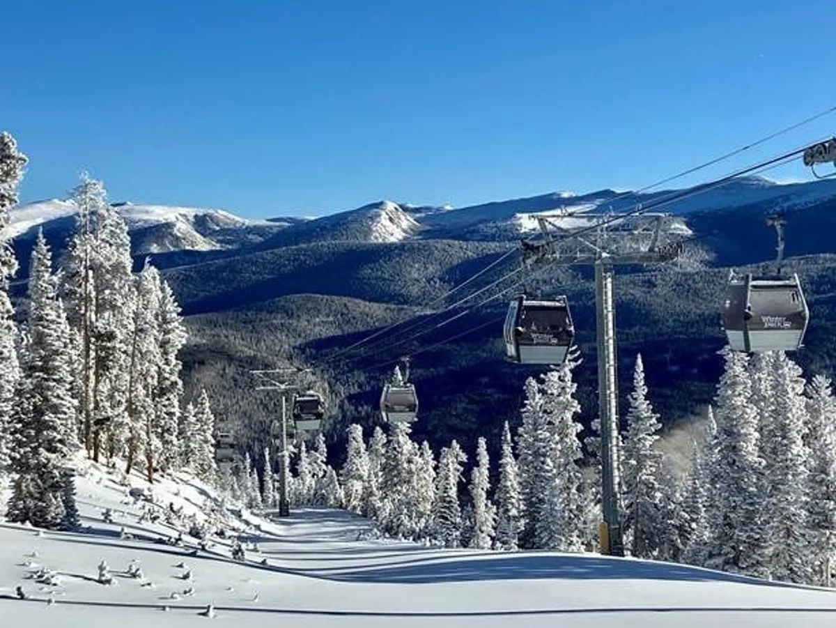 A panoramic view of snow-covered slopes beneath a ski lift, with frosted trees and distant mountains under an adventurous sky. The scene is full of energy, evoking the thrill of skiing, snowboarding, and snow sports in a beautiful high-altitude setting.