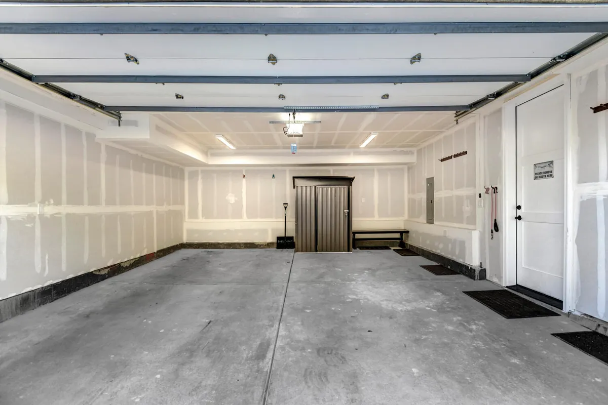 A practical, well-organized garage space featuring a visible garage door, built-in storage units, and a bench. The setting is clean and functional, ideal for storing gear or parking vehicles after outdoor adventures.
