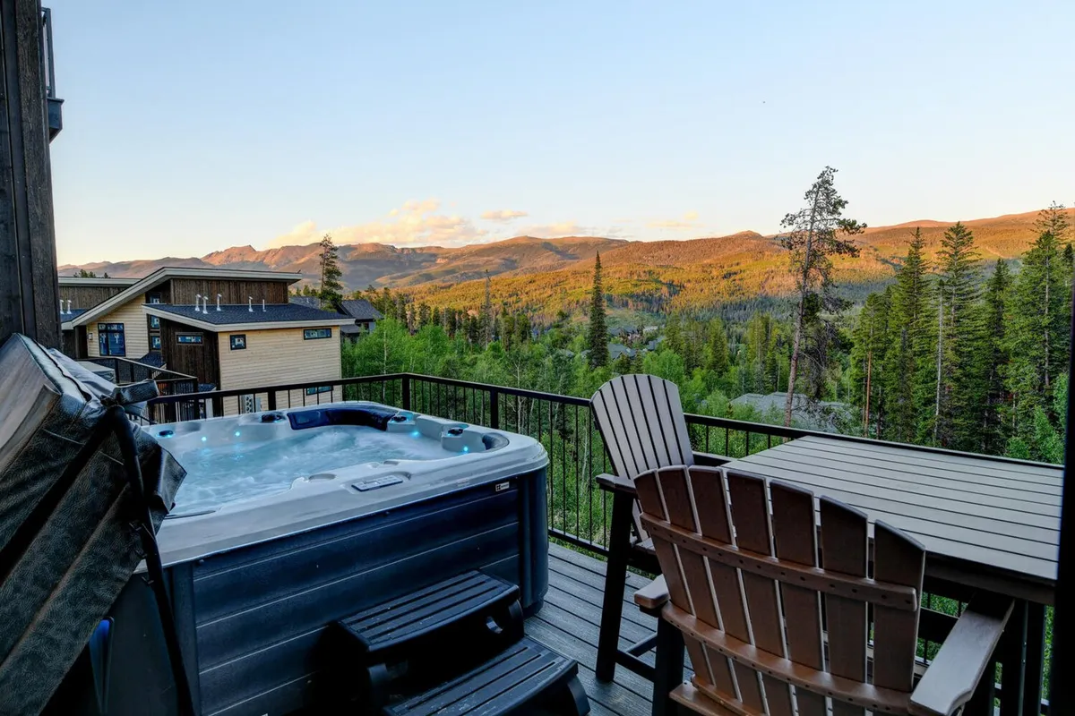 An inviting hot tub on a deck with sweeping mountain views, comfortable seating, and a peaceful ambiance. The outdoor scene is perfect for relaxing after a day of adventure, with opportunities for stargazing or wildlife watching.