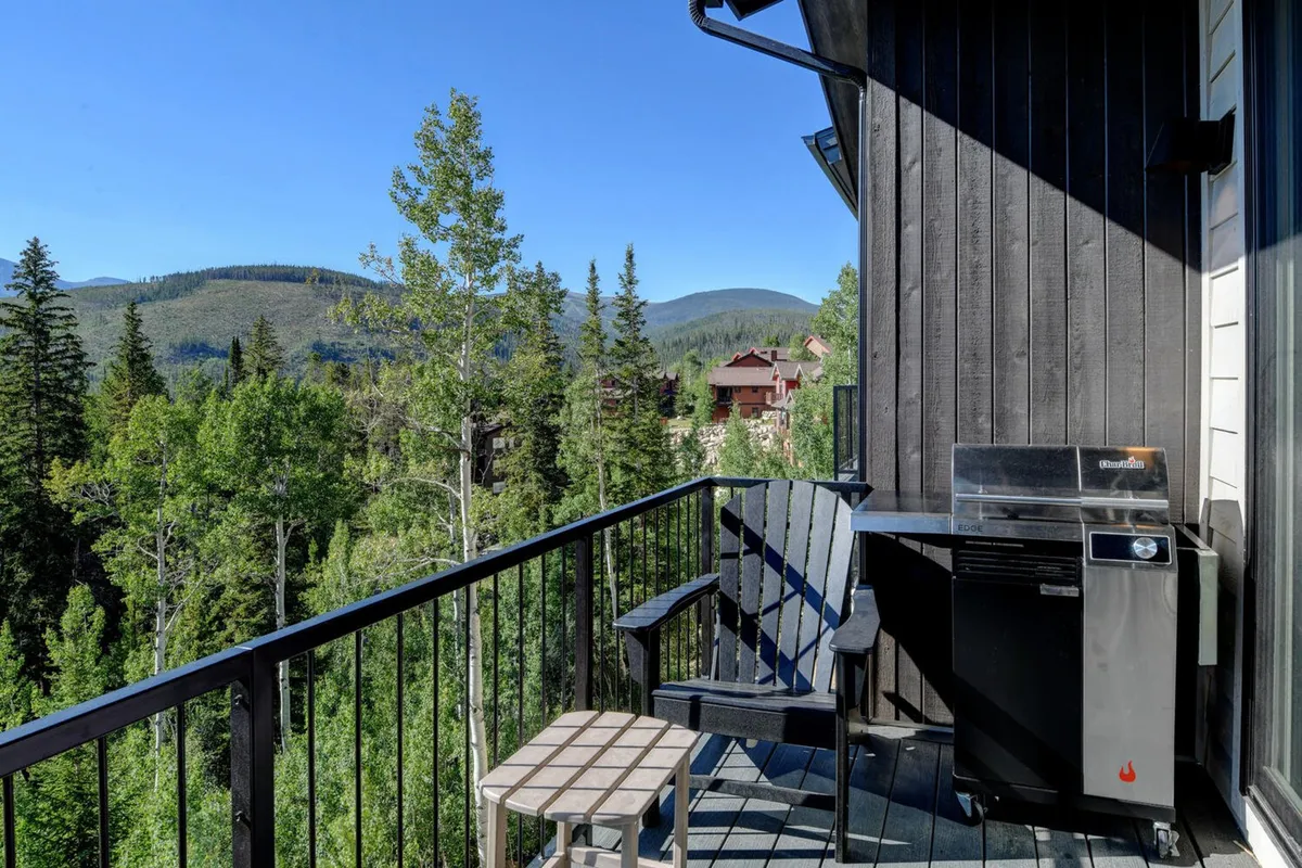 A private outdoor patio with an electric grill, Adirondack chair, and a balcony view overlooking the mountains. The setup is ideal for outdoor dining, grilling under the stars, and enjoying the fresh mountain air in a relaxed, inviting environment.